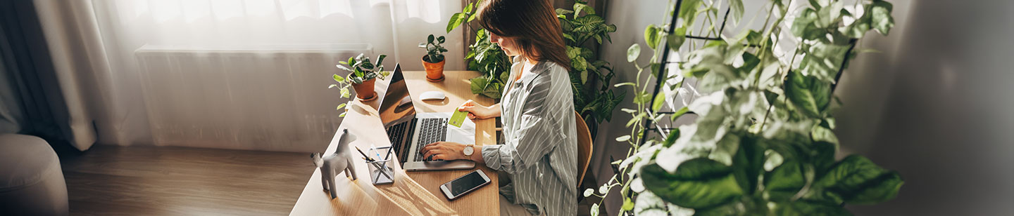 woman at home office desk holding a credit card, June 2024, TCU