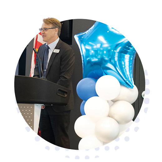 CEO Kevin Miller speaking at the podium, mobile view